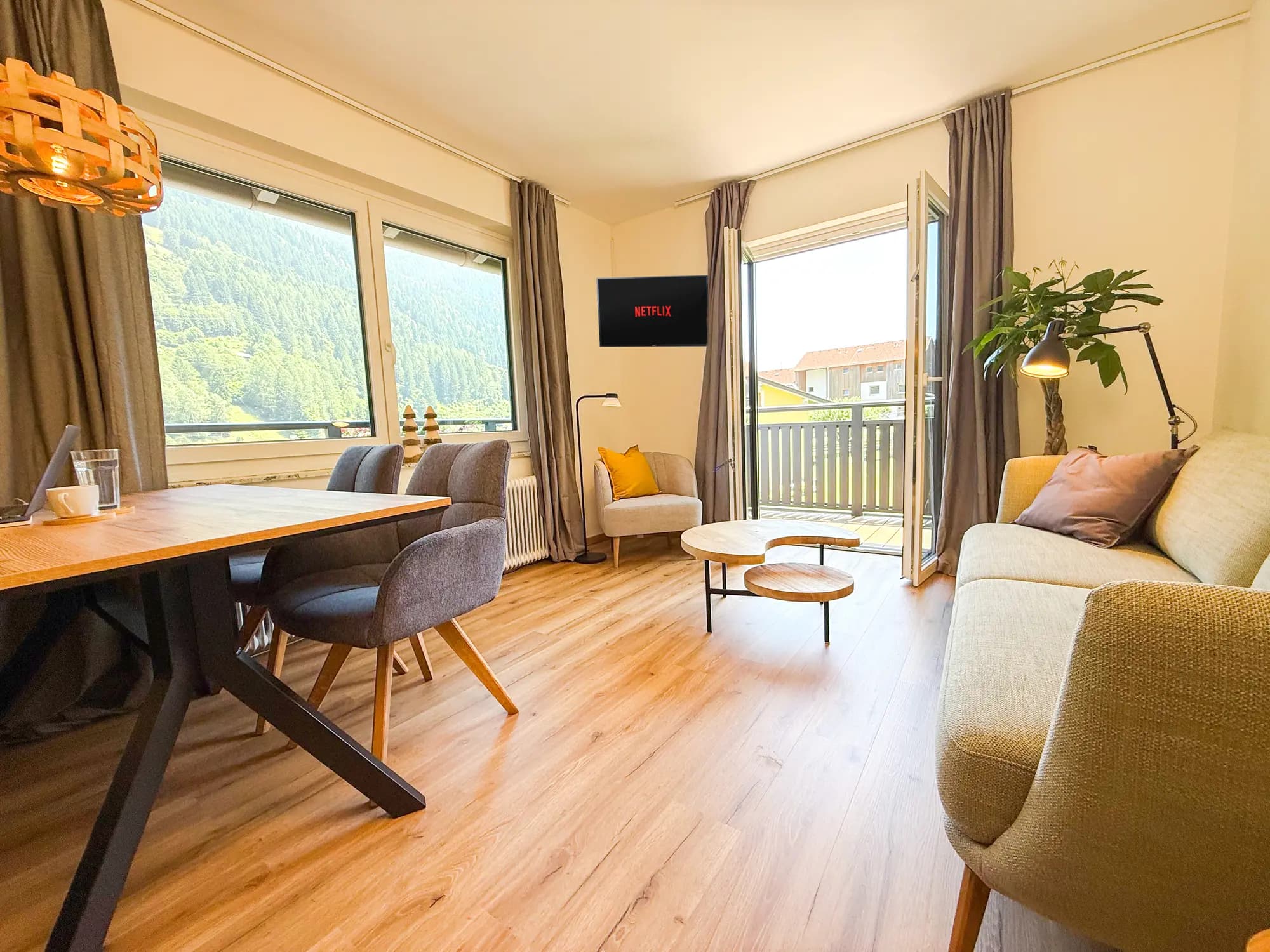 The bright living room of the Steinbock apartment, with dining table, seating area and balcony doors